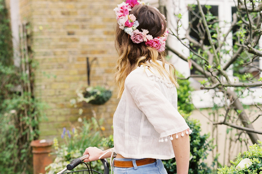 Cara Dawson con camicia bianca e shorts di jeans in bicicletta