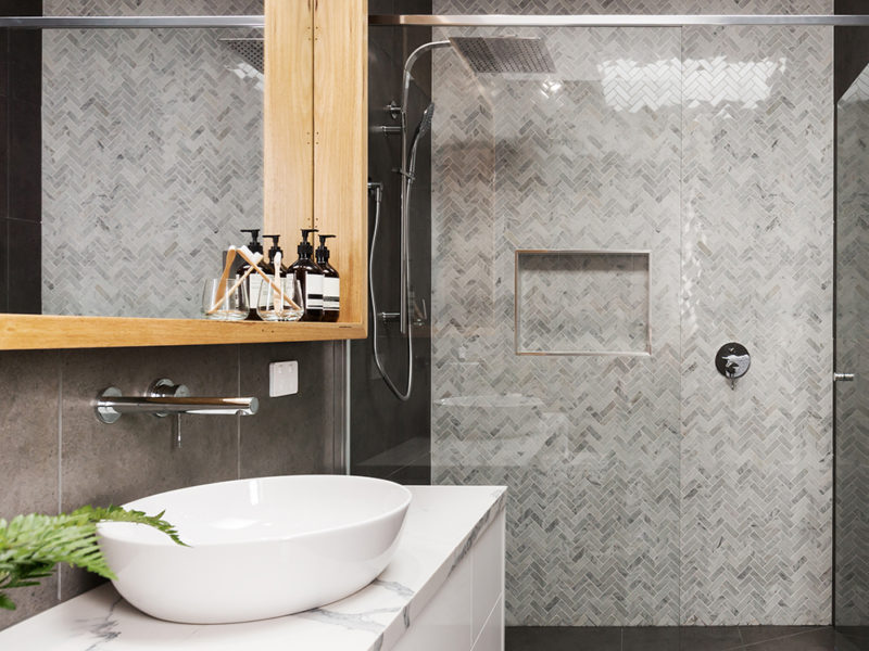 Marble mosaic herringbone tiled shower feature wall in a contemporary ensuite bathroom