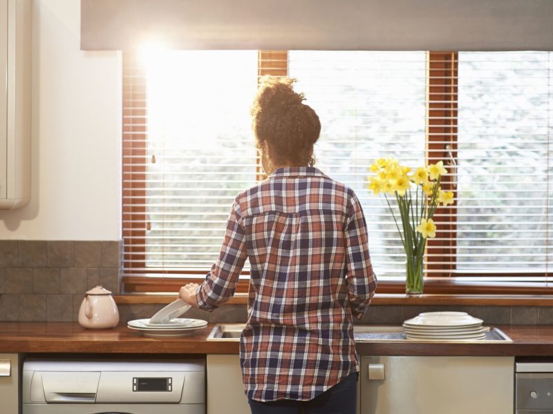 Woman washing up crockery in kitchen - DigitalVision - GettyImages