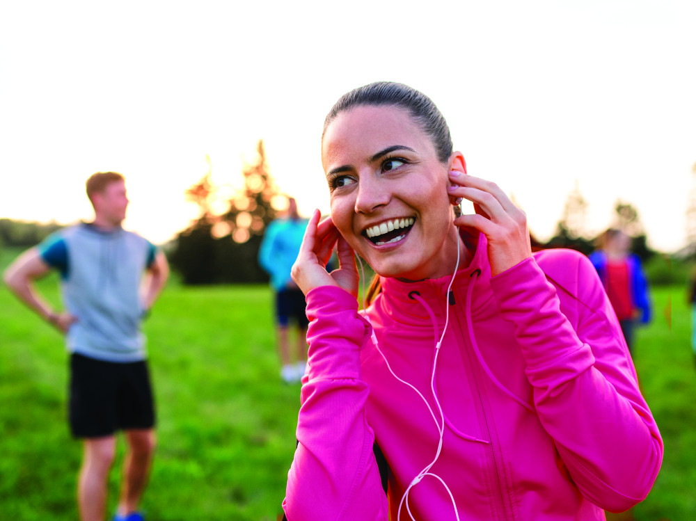 A young woman with group of people doing exercise in nature, resting.