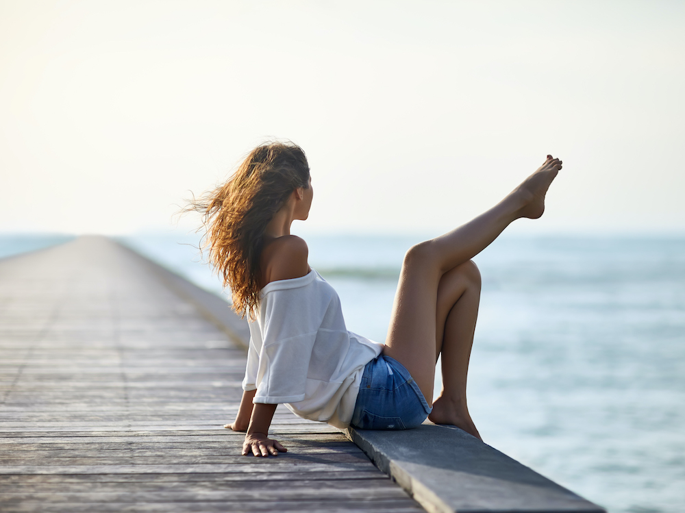 Sexy beautiful woman relaxing on pier with sea view