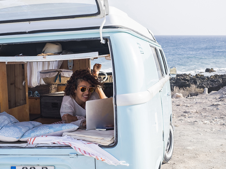 Spain, Tenerife, smiling woman looking at laptop in van