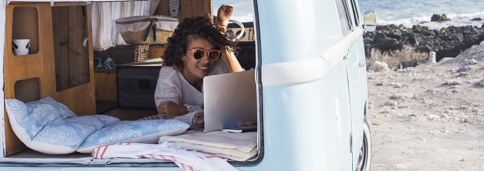 Spain, Tenerife, smiling woman looking at laptop in van