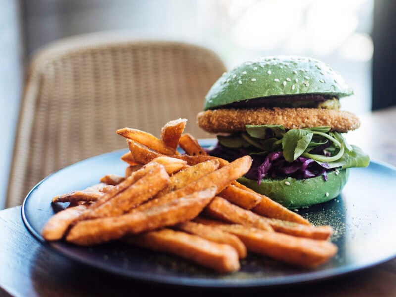 Crumbed tofu burger in a green bun, with sweet potato fries