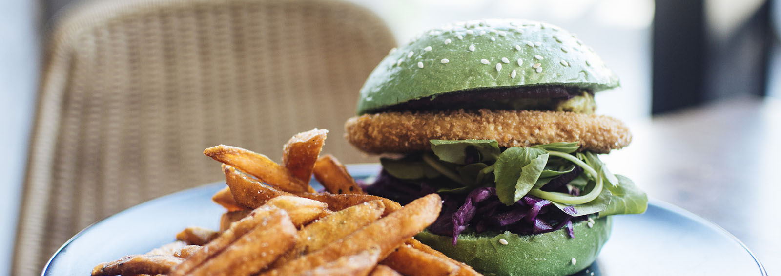 Crumbed tofu burger in a green bun, with sweet potato fries