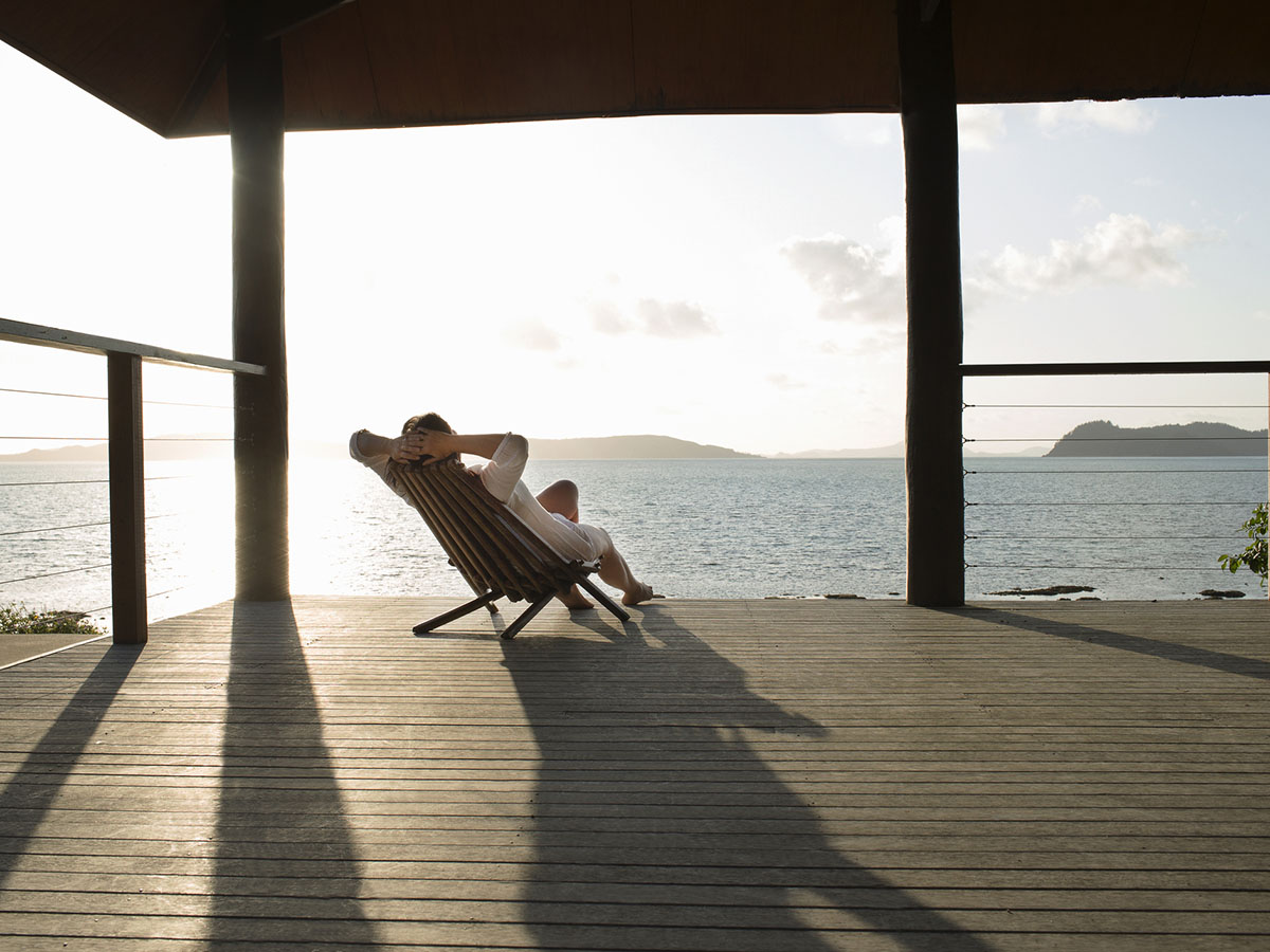 Woman relaxing in deck chair on veranda.