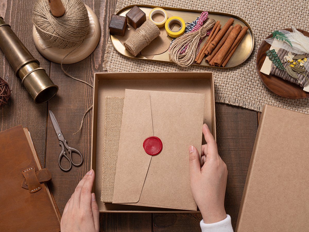 Woman’s Hand Put a Vintage Letter Envelope into Gift Box