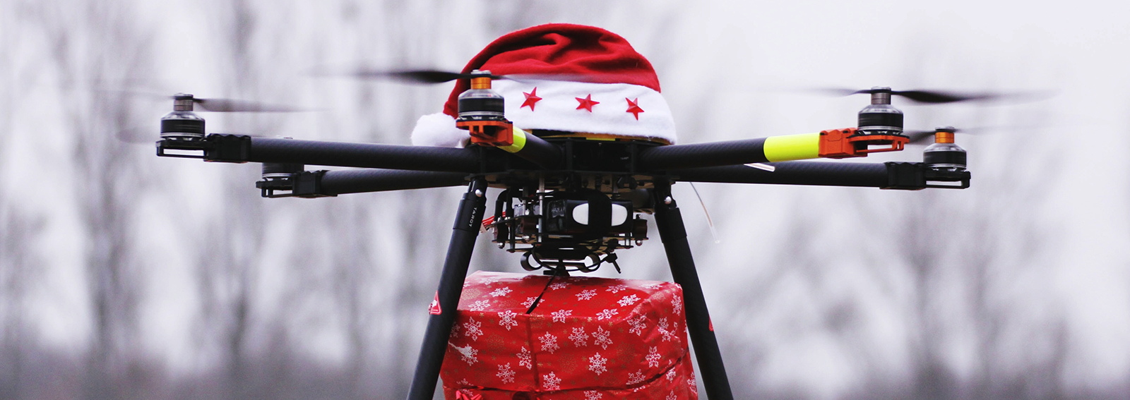 Drone With Santa Hat Carrying Christmas Present Against Sky