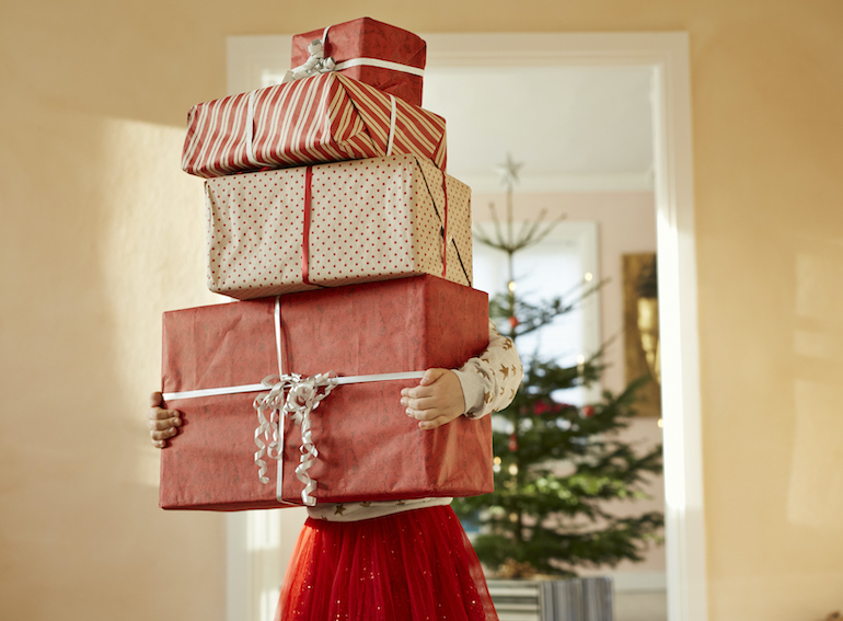 Girl holding tall stack of christmas presents