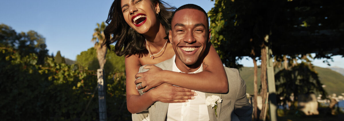 Happy groom piggybacking bride in vineyard