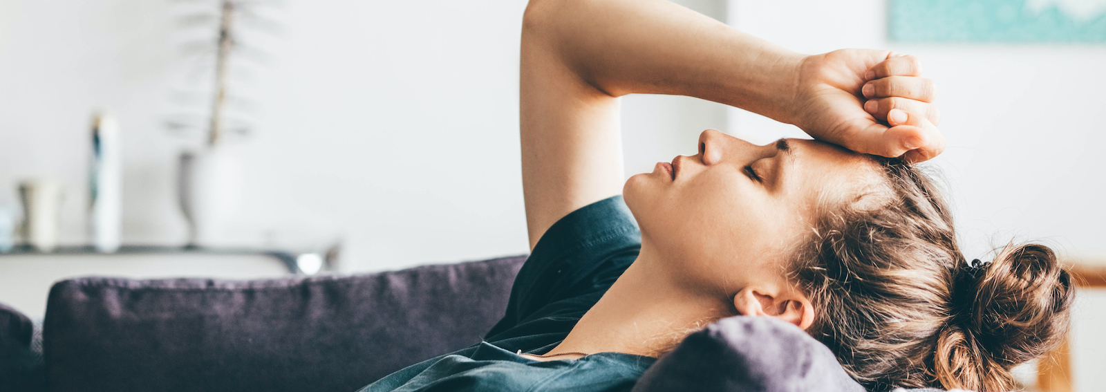Sad and depressed woman sitting on sofa at home.