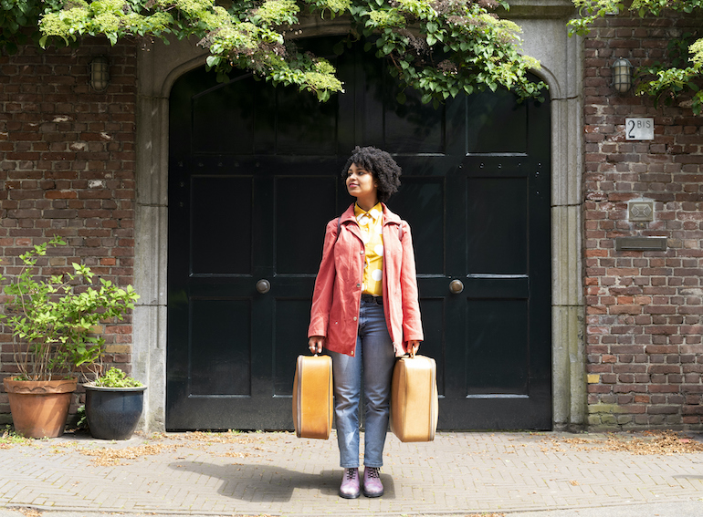 A young woman holding suitcases.