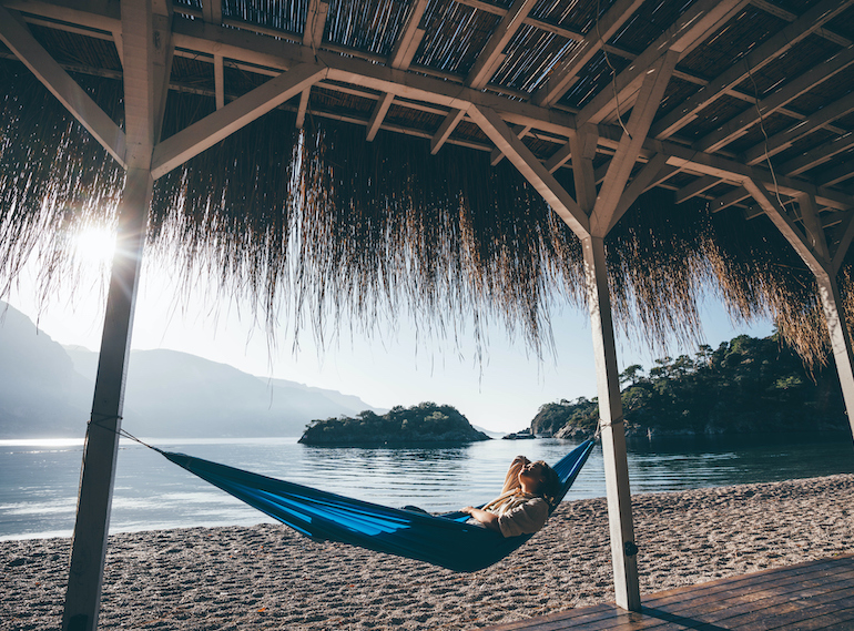 Woman relaxing in hammock on beach