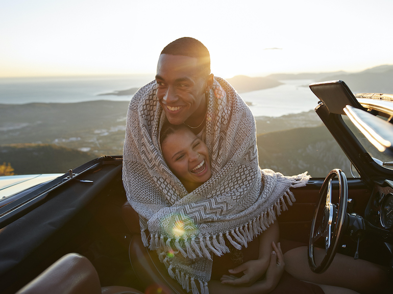 Man embracing girlfriend in convertible car