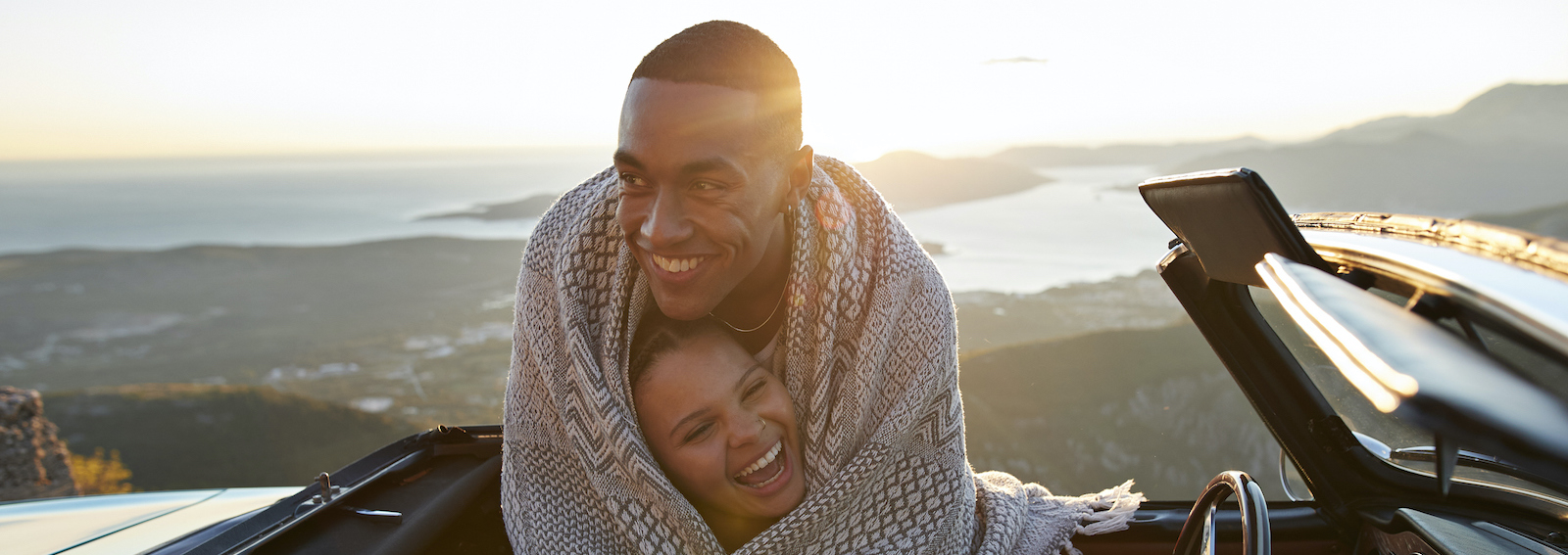 Man embracing girlfriend in convertible car