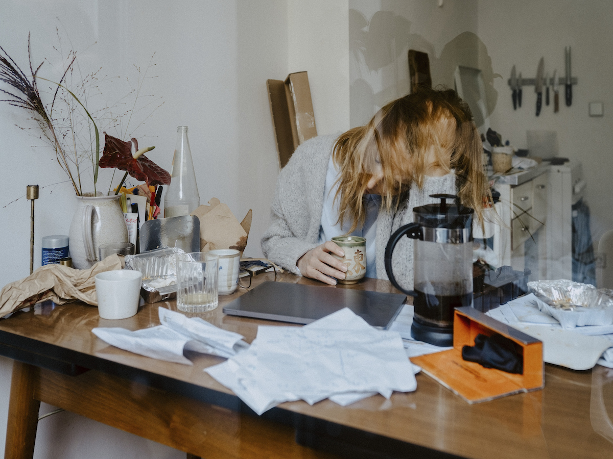 Emotionally stressed businesswoman with coffee cup at table in living room