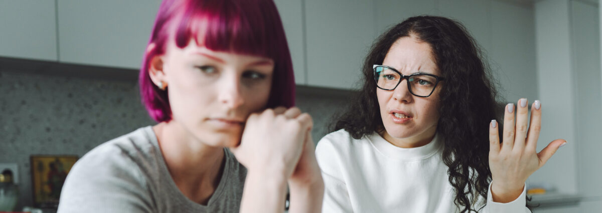 Single working mother and her teenage girl talking sadly in the kitchen