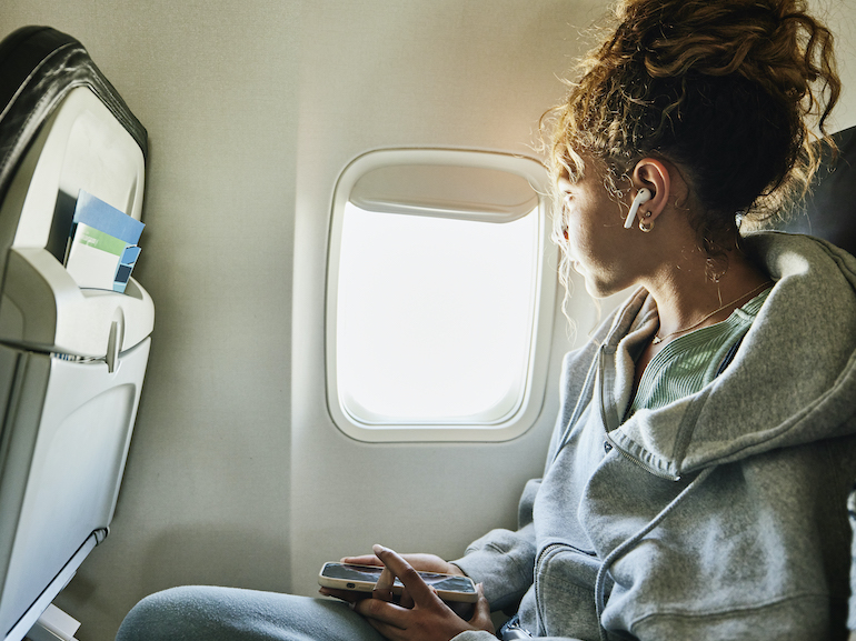 Medium shot of girl looking out window of commercial airplane