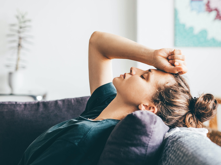 Sad and depressed woman sitting on sofa at home.