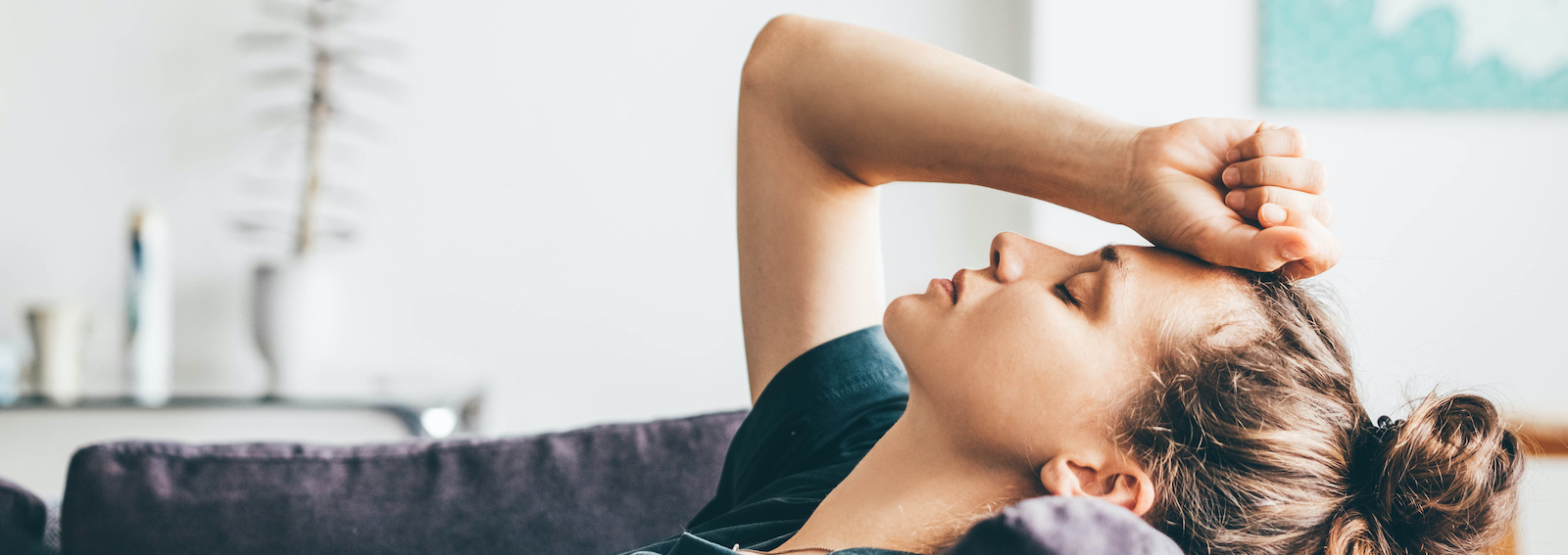 Sad and depressed woman sitting on sofa at home.