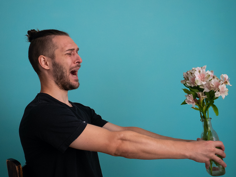 White Man Terrified by Holding Flowers on a Turquoise Background
