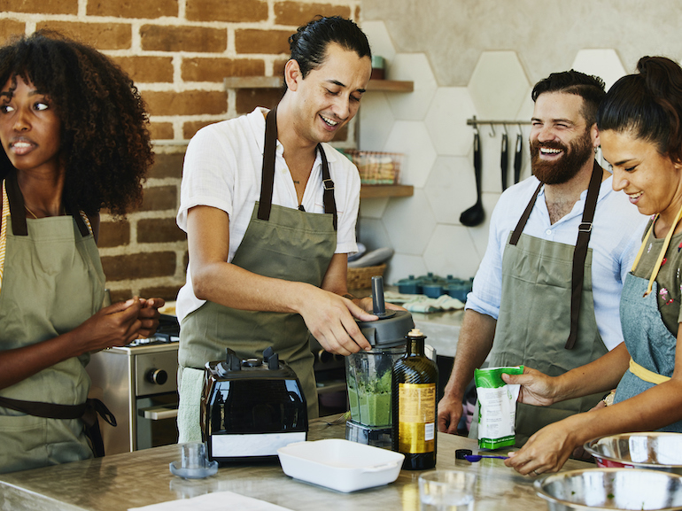 Medium shot of students laughing with female chef during cooking class