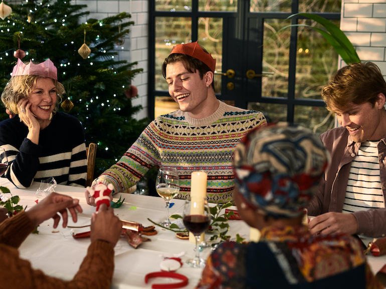 Cheerful family sitting down after Christmas dinner playing games