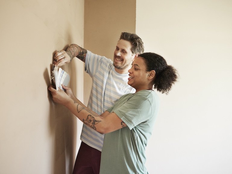 Smiling couple choosing paint color for home