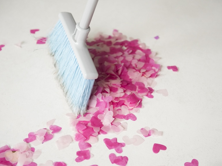 Broom sweeping heart-shape confetti on floor