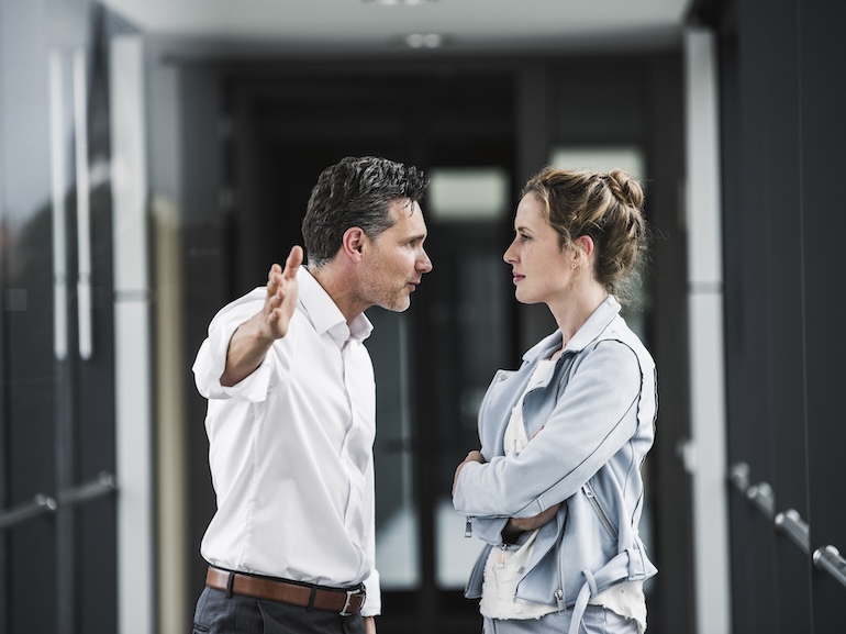 Businesswoman and businessman arguing in office passageway