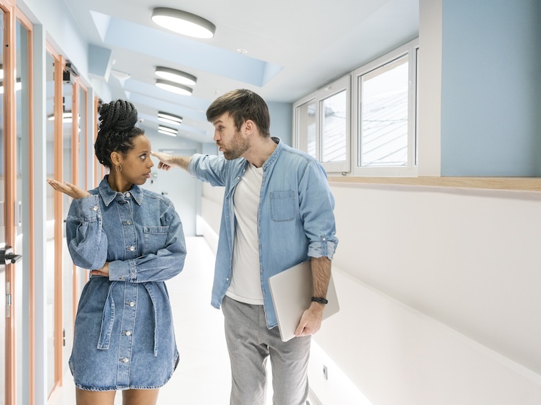 Businessman arguing with female colleague while standing in office corridor