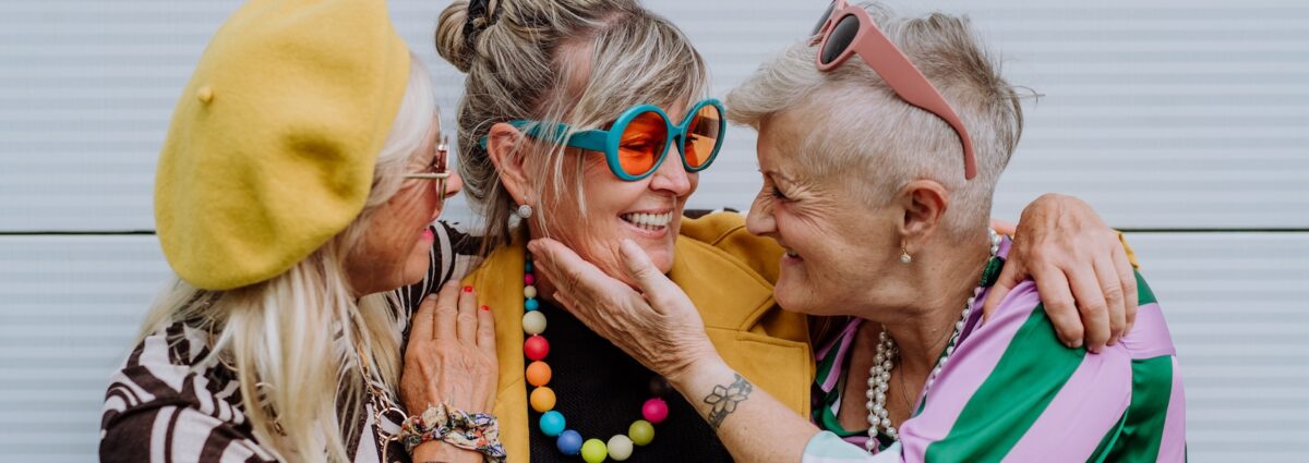 Portrait of happy three senior friends in colourful clothes.