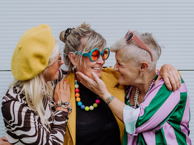 Portrait of happy three senior friends in colourful clothes.