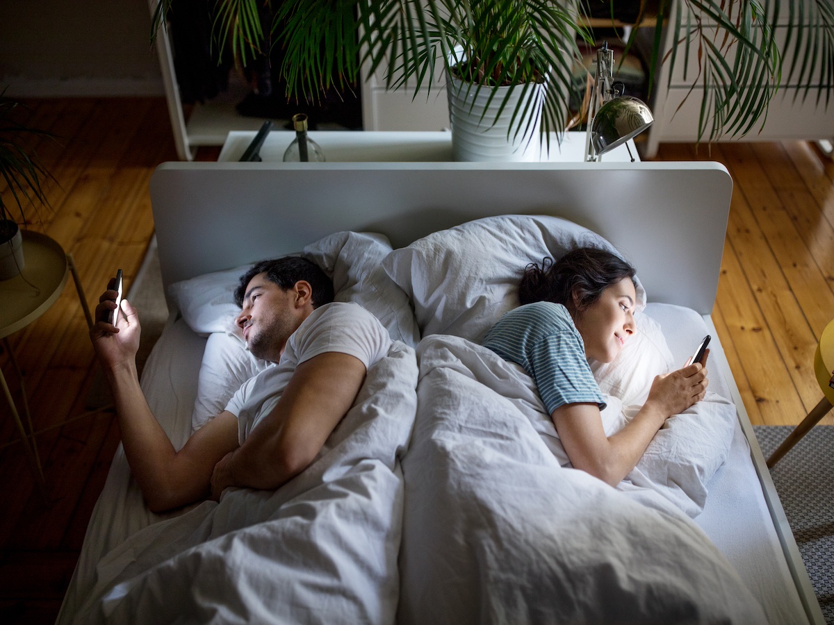 Couple in bed using their mobile phones