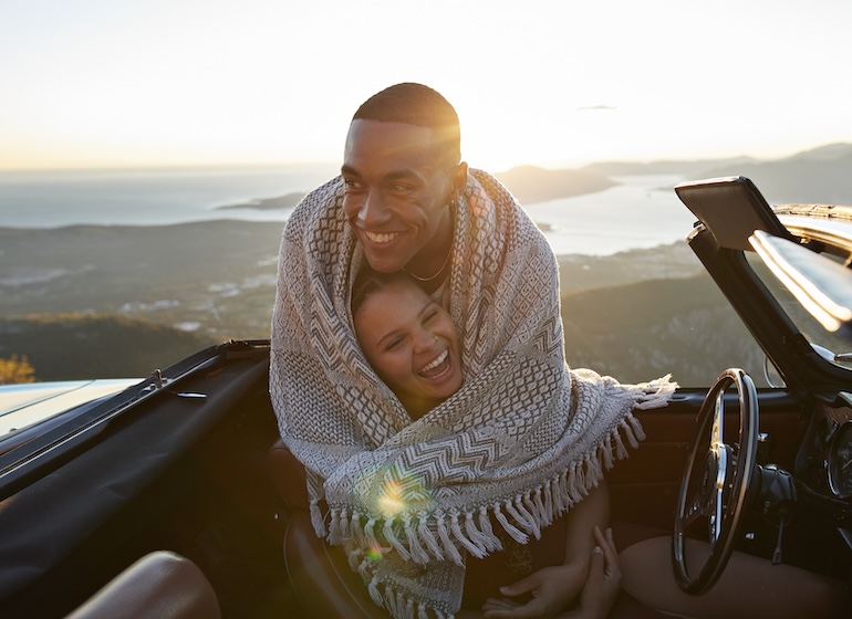 Man embracing girlfriend in convertible car