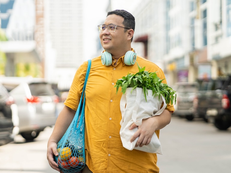 Asian man walking on street with groceries on hands