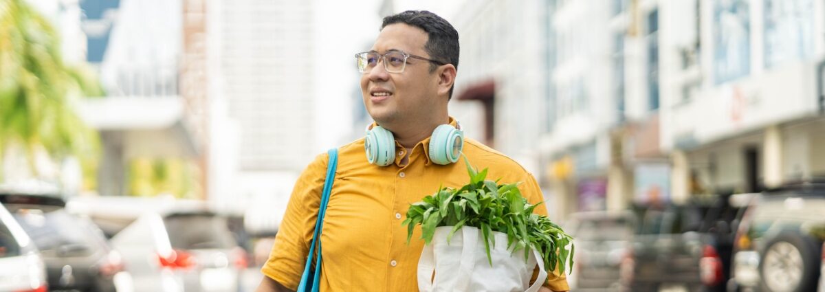 Asian man walking on street with groceries on hands
