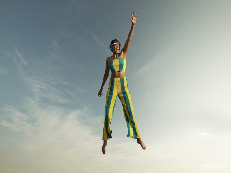 Woman levitating while raising hand against sky