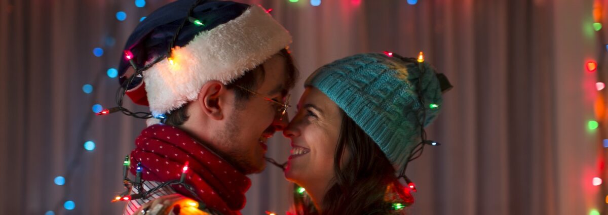 Romantic young couple wrapped in decorative lights at christmas