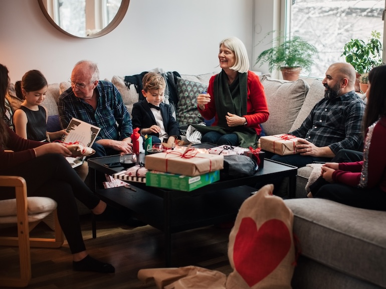 Boy showing Christmas presents to multi-generation family at living room