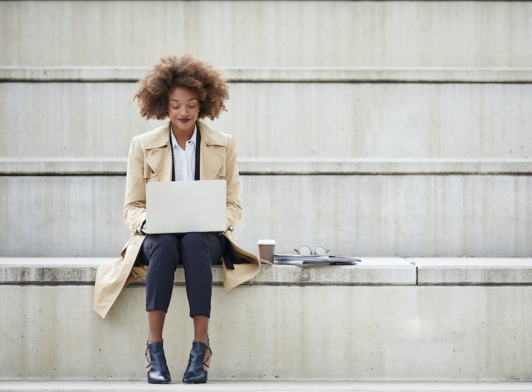 Young businesswoman using laptop on steps