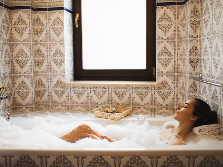 Attractive young woman keeping eyes closed while enjoying luxurious bath.