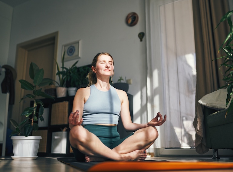 Woman enjoys a peaceful moment in meditation, embraced by the warmth of her home.