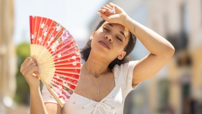 Una persona beve acqua durante la giornata, con un bicchiere a portata di mano in ufficio, mentre si sforza di mantenere un'igiene idrica adeguata