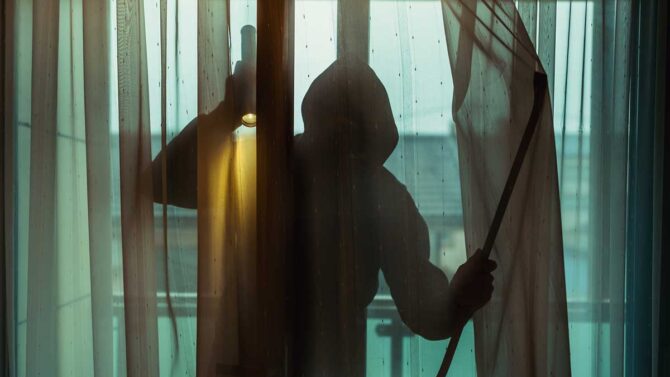 Una casa con porte e finestre chiuse, allarme attivo e luci accese, con un vicino che osserva la scena